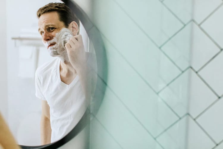 A man putting shaving cream on his face
