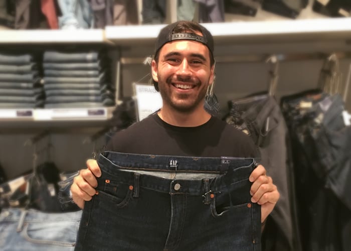 A man holding a pair of jeans and smiling
