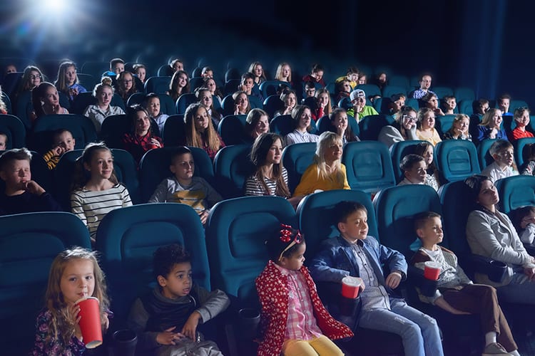 A crowd of children and teens in a movie theatre 