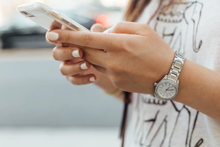 A woman wearing a watch holding an iPhone