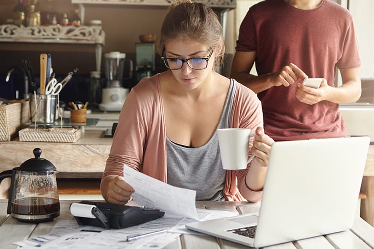 A woman holding a cup of coffee while looking at paperwork