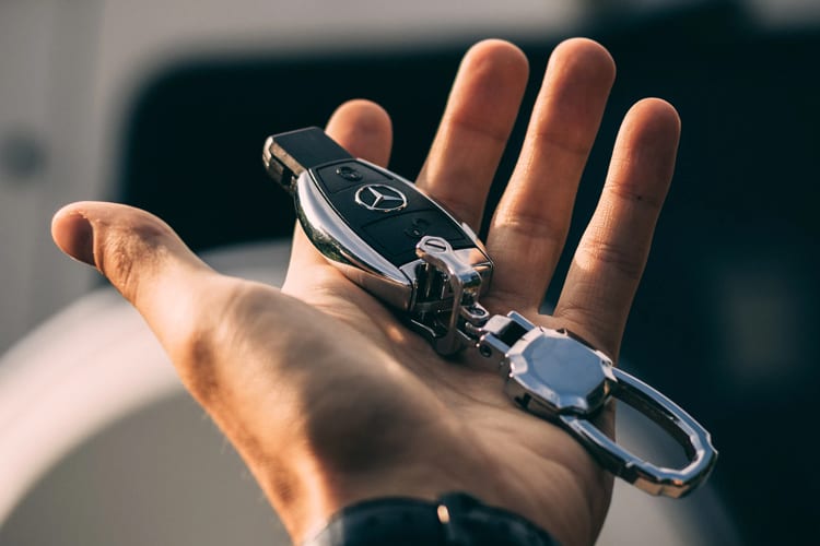 A hand holding the keys to a Mercedes