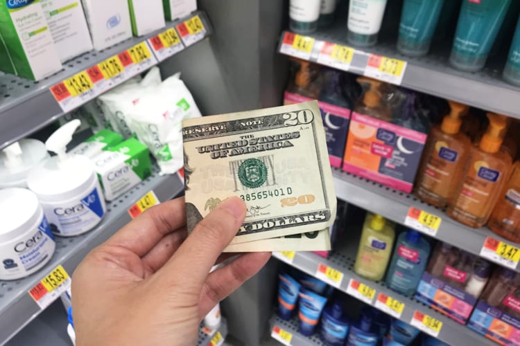 A person holding a $20 bill while shopping for cosmetics 