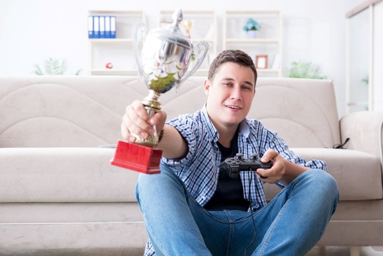 A man holding a game controller and a trophy