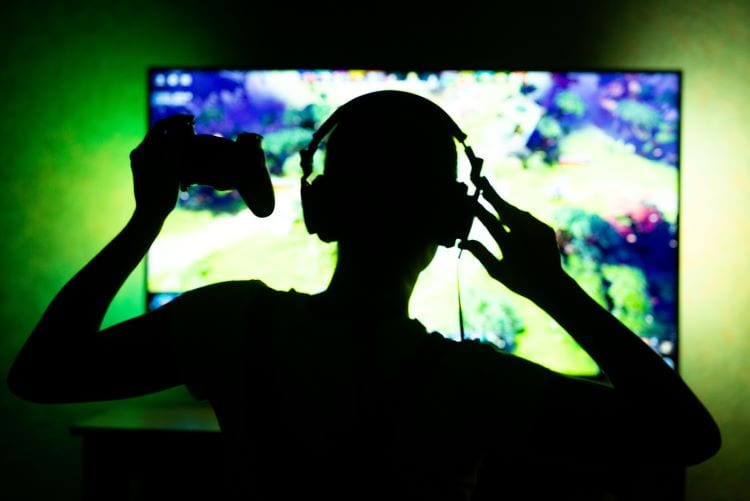 A gamer wearing a headset and looking at a large flat screen