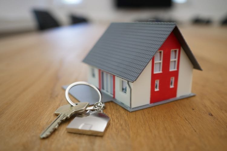 A set of keys next to a miniature house on a table