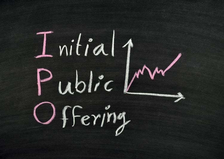 The words "initial public offering" written on a chalkboard next to a line graph