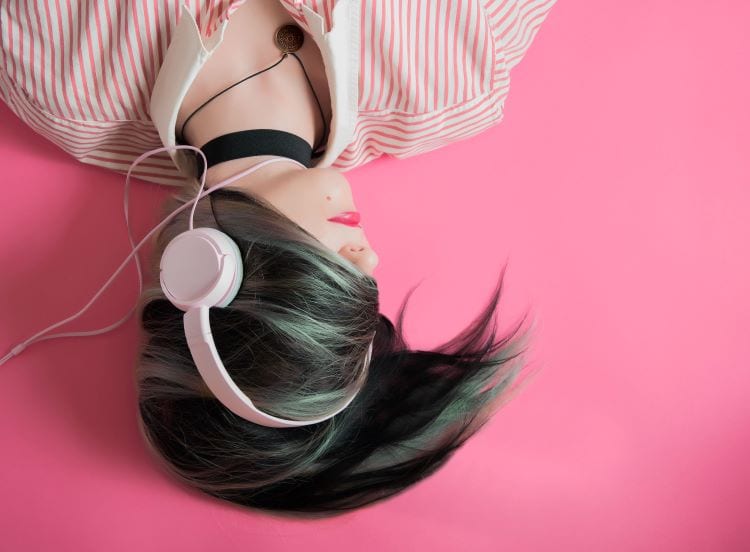 A woman upside down wearing pink headphones