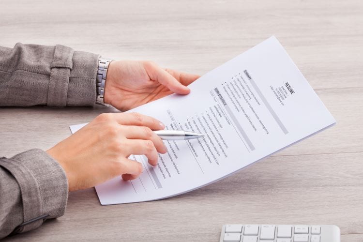 A person holding their resume and a pen