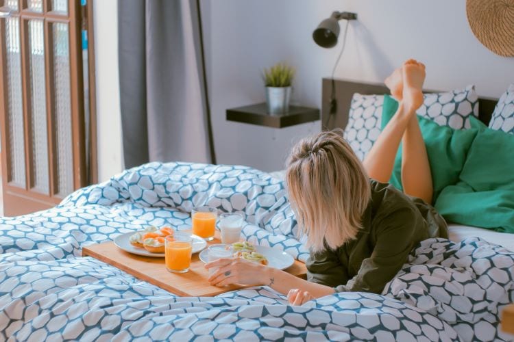 A woman enjoying breakfast in bed with her feet up 