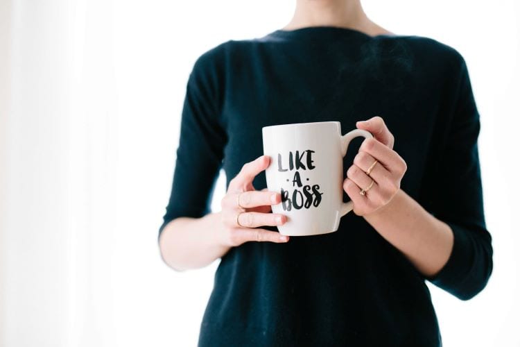 A woman holding a coffee mug that says "like a boss" 