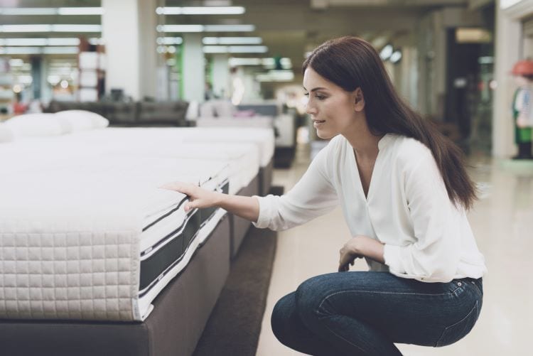 A woman in a mattress store inspecting a bed