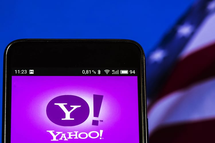 A phone showing the Yahoo! app with an American flag behind it 