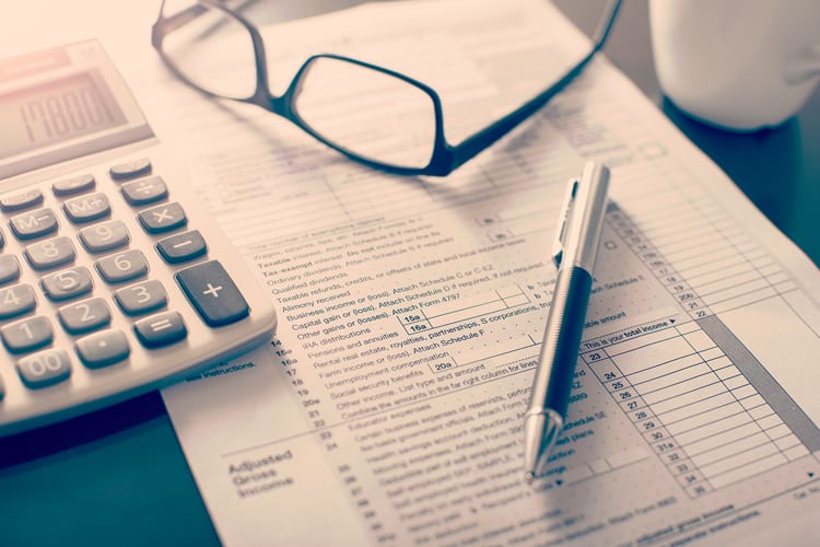 A tax form, a calculator, glasses, and a pen