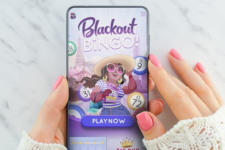 Female hands with pink manicure holding a phone displaying Blackout Bingo