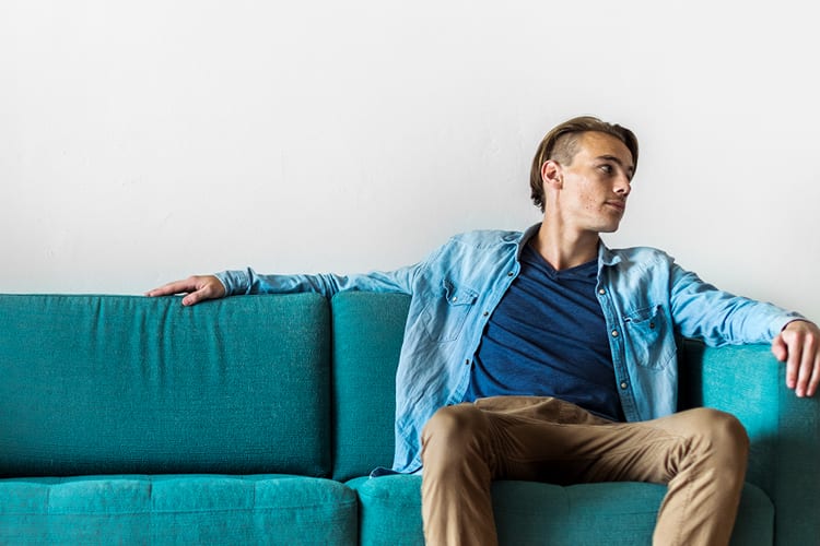 A young man sitting on a teal couch