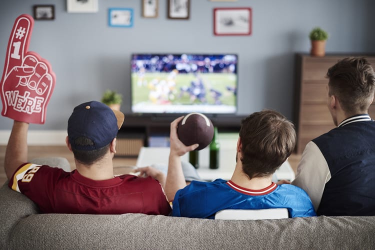 Three men watching a football game on a couch together