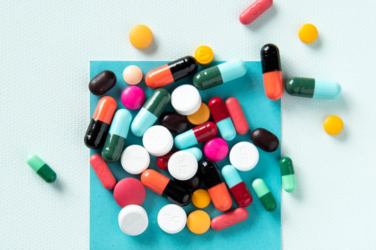 Various pills and medicine capsules on a blue post-it 