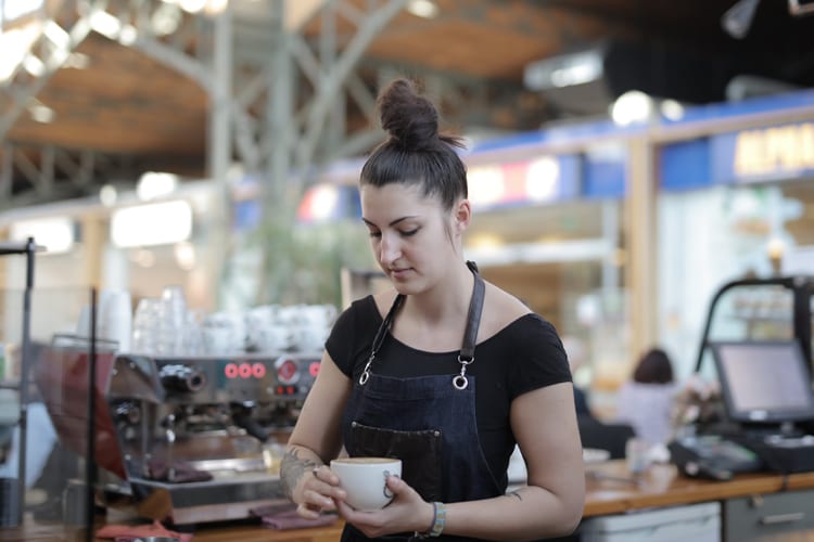 A barista preparing an espresso behind the counter at a coffee shop