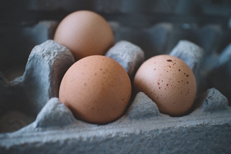 A close-up of three eggs in a carton