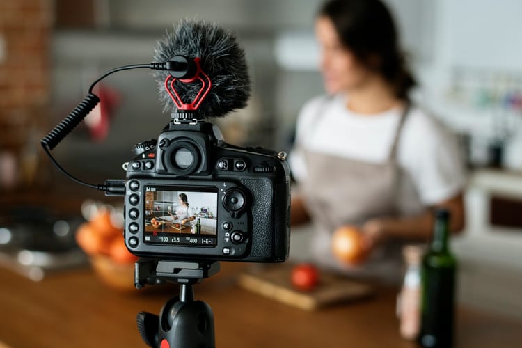 A woman filming herself cooking in her kitchen
