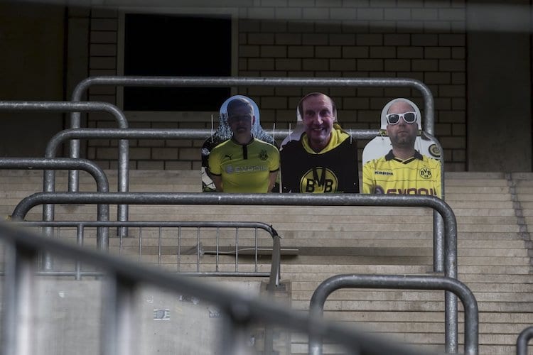 The stands of a German soccer stadium with three cardboard cutouts of fans