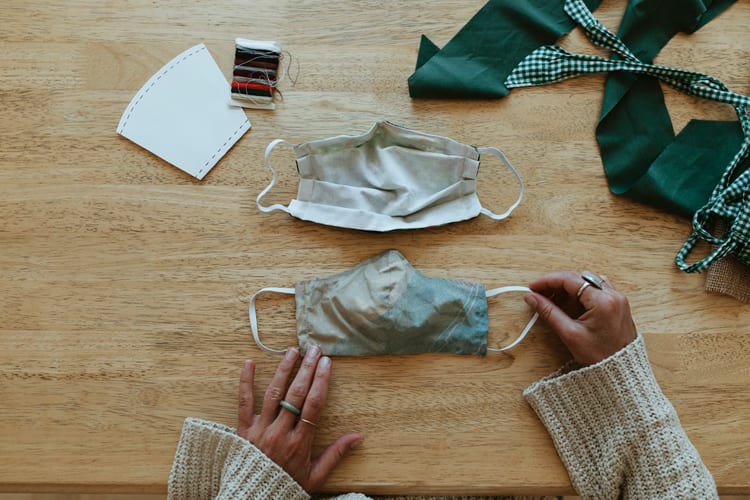 A woman's hand sewing two cloth face masks
