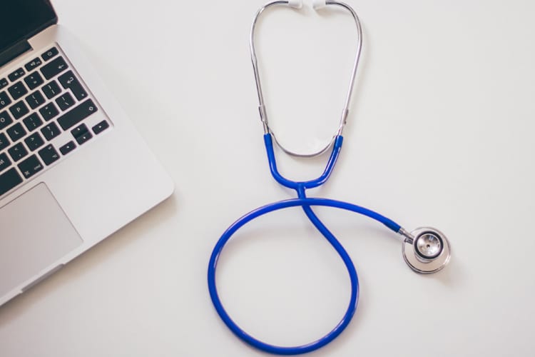 A stethoscope next to a laptop