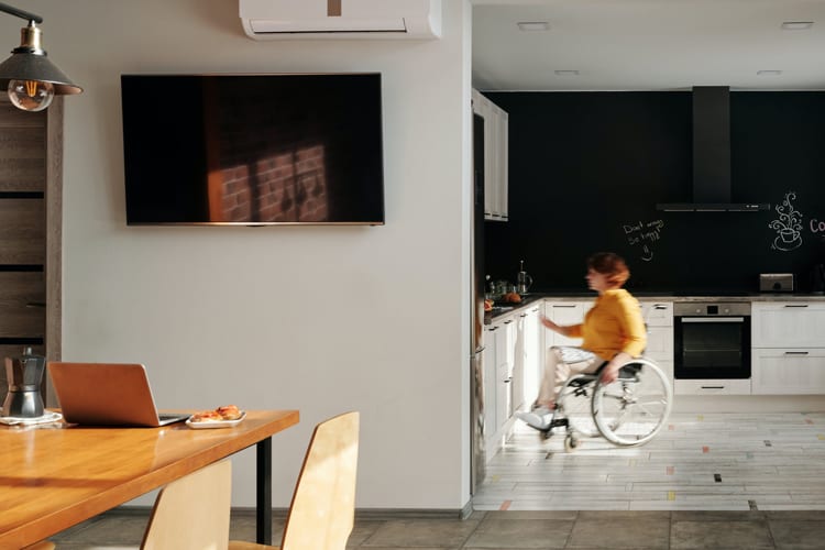 A person in a wheelchair in the kitchen of an apartment