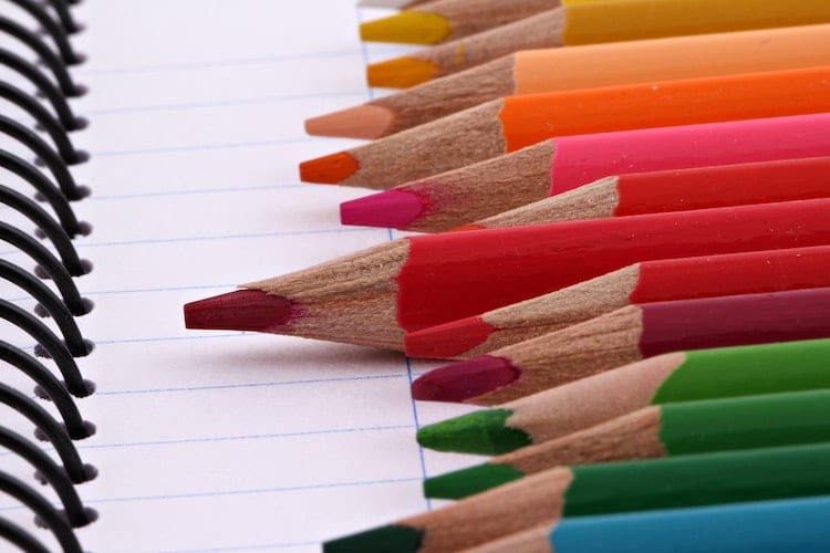 Colored pencils arranged by the rainbow on a notebook