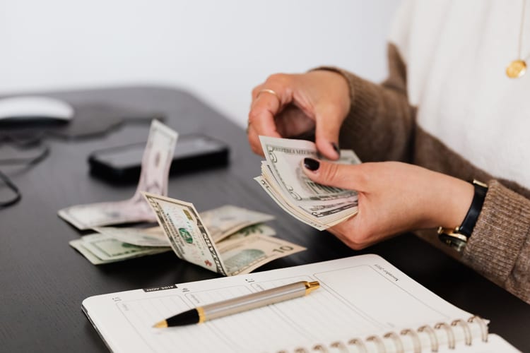 Female hands counting cash at a desk with day planner by side