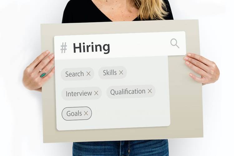 Woman holding a sign that says Hiring with job related skill search keywords
