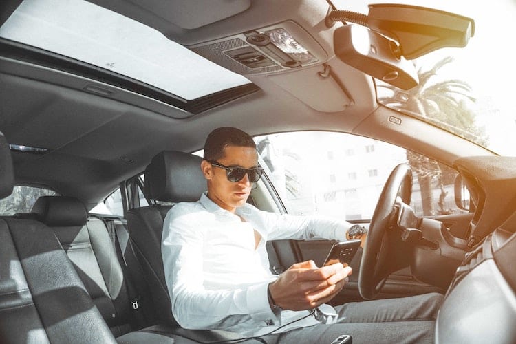 A man driving a car while looking at his phone