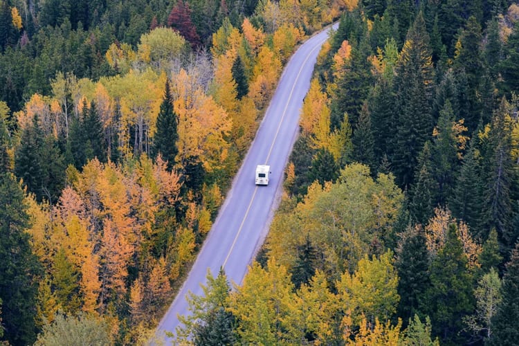 Drone view of an RV on the road surrounded by fall season trees