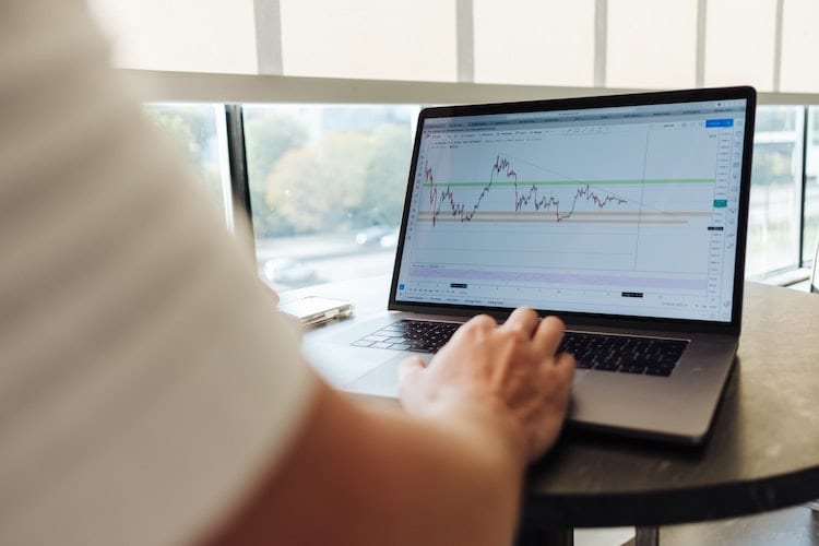A man looking at a laptop displaying a stock chart