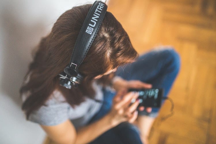 A woman wearing headphones and listening to music on her phone