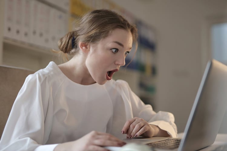 Office woman staring at her laptop in shock with mouth open
