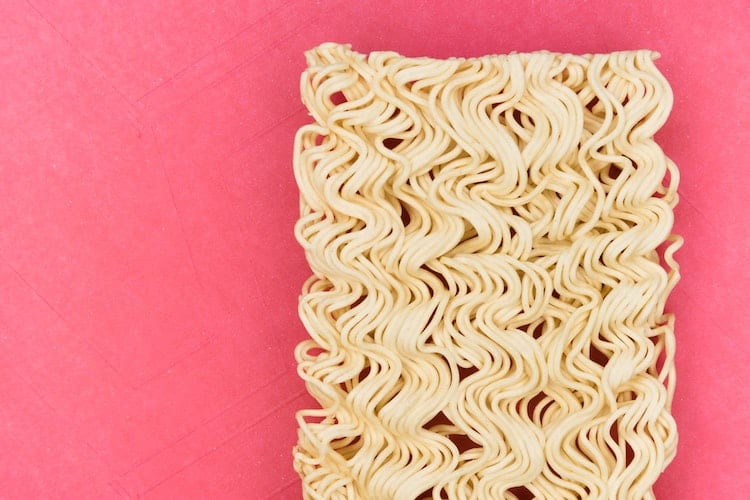 Uncooked ramen noodles on a pink background