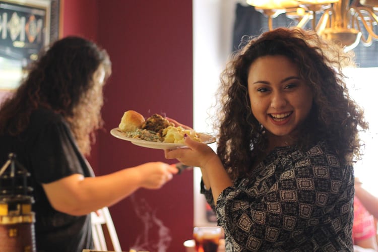 Latina woman smiling holding a dinner plate of food