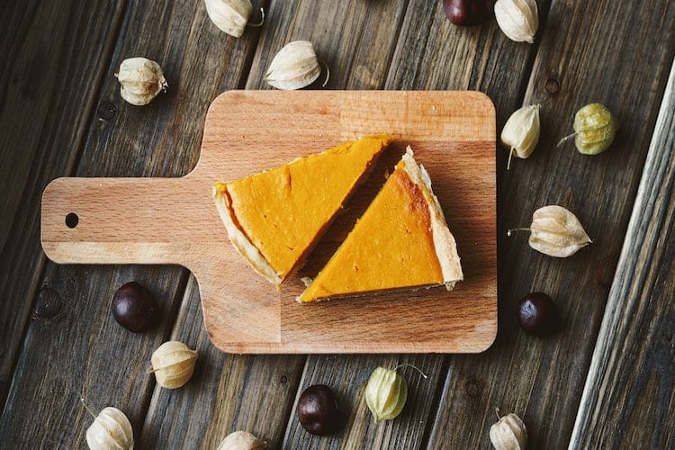 Two slices of pumpkin pie on a cutting board