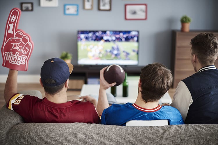 Three guys sitting on a couch watching football