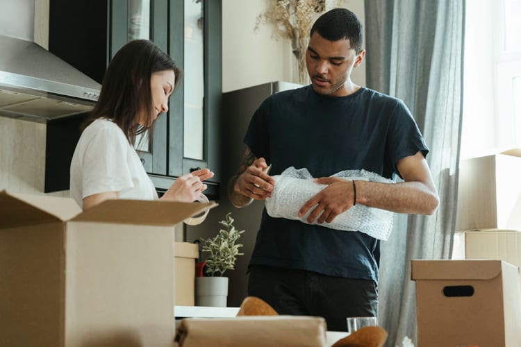 A mixed couple packing boxes in the kitchen to prepare for a move