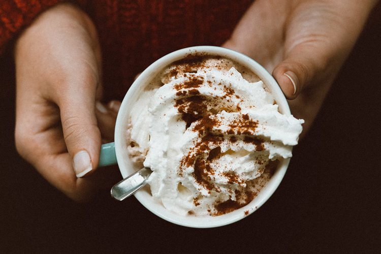 Pair of hands holding hot chocolate with whipped cream